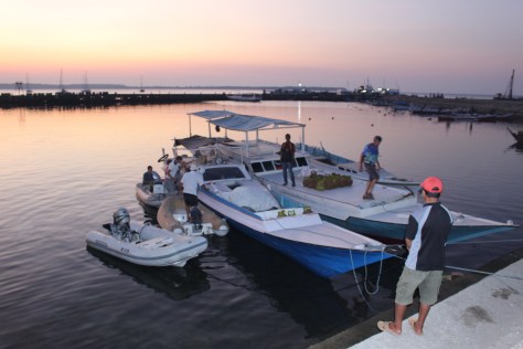 Landing the dinghies; our boats anchored outside the breakwater