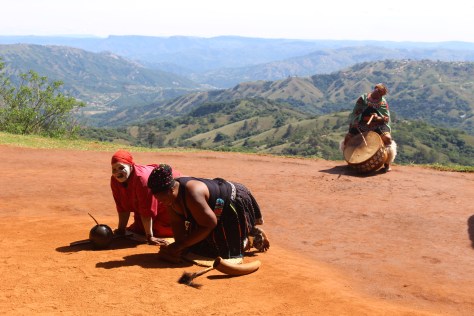 Next step is to consult with the shaman (in black; can be male or female). The woman in red and painted face/body is a shaman in training.